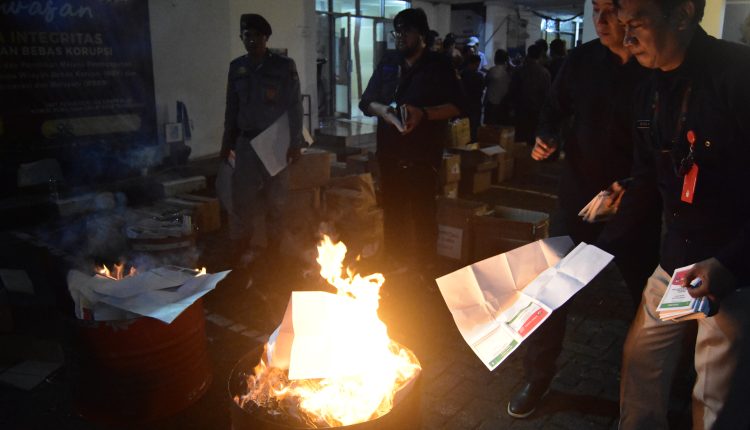 Beberapa petugas KPU sedang membakar kertas suara yang rusak dan lebih
