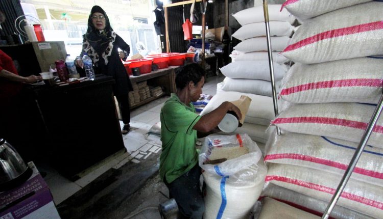 Penjual beras sedang melayani pembeli beras