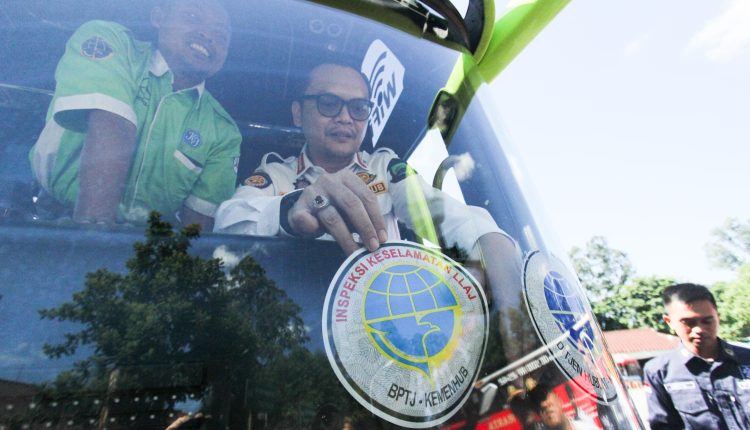Kepala Dishub Kota Tangerang, Achmad Suhaely sedang menempelkan stiker di kaca depan salah satu bus yang sudak lulus ramp check dan layak jalan