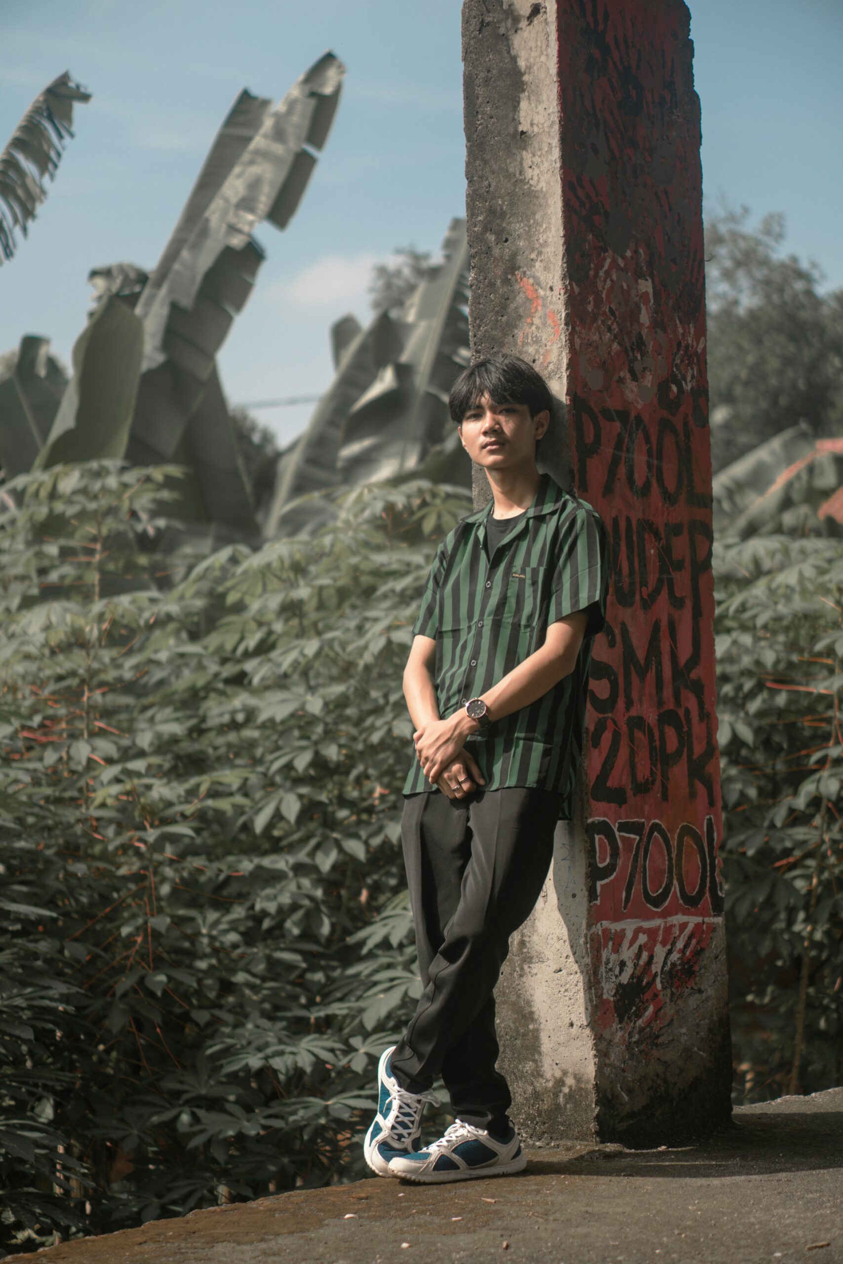 a man standing next to a tree with graffiti on it